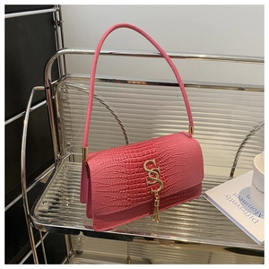 Detail of pink croc-embossed handbag featuring gold metal logo and fringe tassel charm