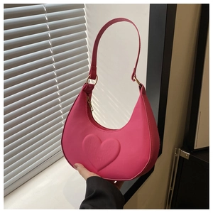 Detail shot of hot pink hobo bag with embossed heart pattern and golden hardware