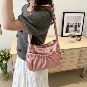 Chic pink satin hobo bag with bow decoration shown on shoulder in a cozy home setting