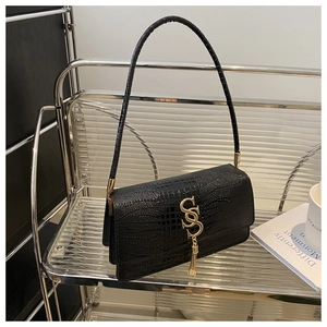 Close-up of black croc-embossed shoulder bag featuring gold metal fringe logo detail
