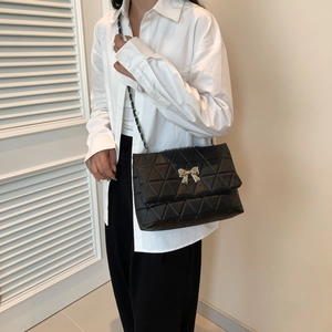 Elegant black quilted crossbody bag with silver bow detail and metal chain strap