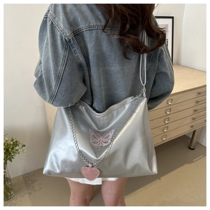 Close-up of silver tote bag featuring pink butterfly embroidery and heart chain detail