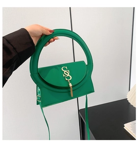 Detail der modischen grünen Handtasche mit rundem Griff und goldener Quaste aus Metall