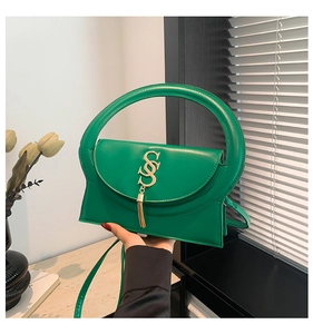 Smaragdgrüne Umhängetasche mit halbrundem Griff und goldenem S-Logo mit Quaste