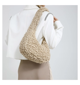 Dettaglio della borsa a spalla beige con texture popcorn su completo blazer bianco