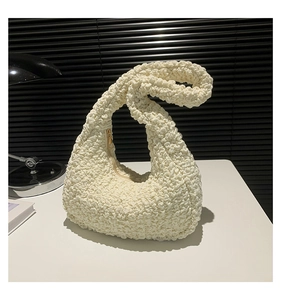 Dettaglio del tessuto a bolle color crema su una borsa a mezzaluna con zip dorata