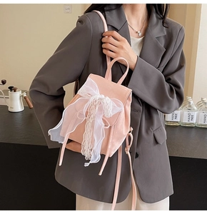 Detail of pink faux suede mini backpack with a delicate lace bow and ribbon decor