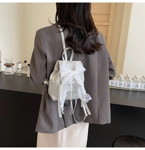 Detail showing the white lace bow on the silver grey mini backpack with thin straps