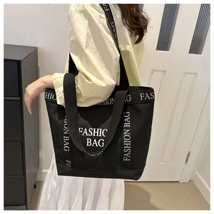 Detail view of large black canvas tote bag featuring white FASHION BAG letter printing