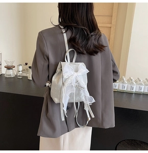 Silver mini backpack featuring a stylish oversized white lace bow detail and metallic finish