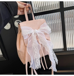 Detailed close-up of a pink mini backpack featuring a large white lace bow decoration