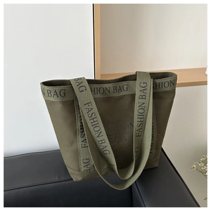 Detailed shot of olive green canvas tote bag with fashion lettering on a leather sofa