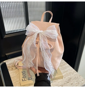Close-up of pink backpack with large white lace bow and drawstring closure detail