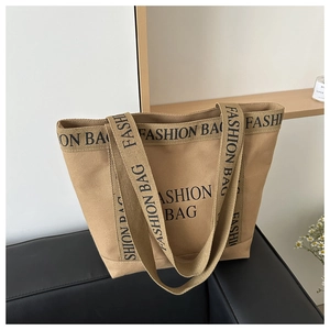 Detail view of khaki canvas tote bag with black Fashion Bag lettering on sofa