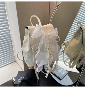 Close-up of mini cream backpack featuring delicate white lace bow and drawstring flap