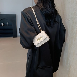 Borsa a tracolla trapuntata bianca con catena dorata su sfondo di blazer in raso nero
