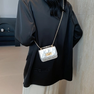 Mini borsa trapuntata argento con chiusura dorata e tracolla a catena su modella