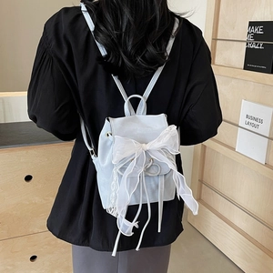 Light blue mini backpack with a large lace bow and drawstring closure shown on model
