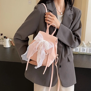 Pink mini backpack for women featuring a large white lace bow and elegant leather finish