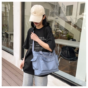 Outdoor lifestyle view of large morandi blue nylon tote bag with functional pockets