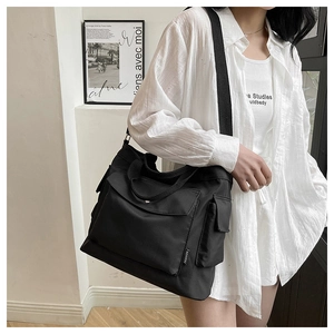 Detail of black large capacity nylon tote bag with functional pockets and fashion label