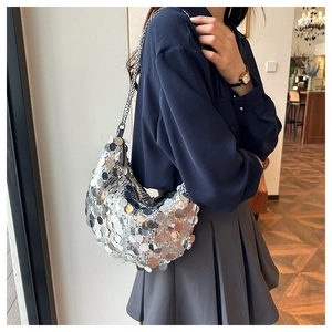 Silver sequin shoulder bag shown on model featuring metal chain and crescent shape