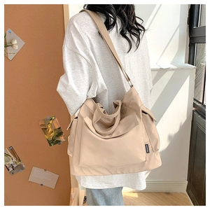 Detail of a large beige nylon shoulder bag showing high-density fabric and utility pockets
