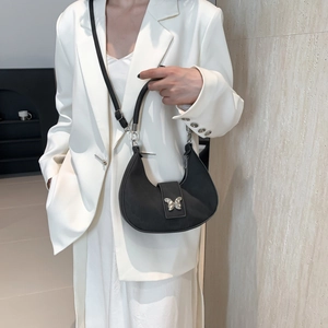 Borsa hobo nera minimalista con fibbia a farfalla argentata su completo bianco elegante