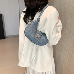 Borsa a mezzaluna in denim blu con fibbia a farfalla argentata indossata da modella in bianco