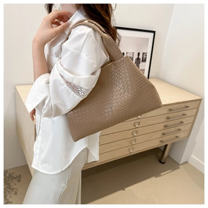Bolso tote marrón con textura tejida en modelo para mostrar el tamaño y el ajuste