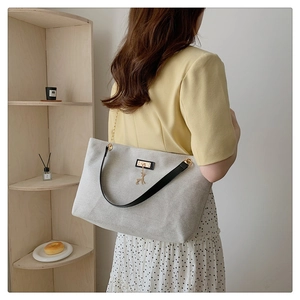 Detail of grey canvas tote bag with black leather straps and golden deer charm
