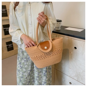 Detailed view of handmade woven straw tote with leather flap and elegant pearl closure