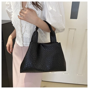 Detailed view of black woven texture on a large bucket bag with stylish top handles