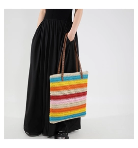 Détail de la texture d'un sac cabas tissé à rayures multicolores avec anses en cuir brun
