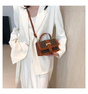 Detailed close-up of retro monogram pattern and gold metallic lock on brown crossbody bag