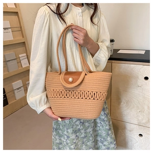 Detail of woven straw handbag featuring a brown leather flap and large pearl closure