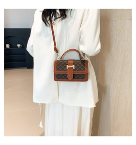 Detail of vintage brown monogram crossbody bag with H-buckle worn by a model