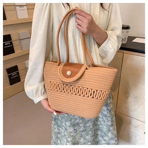 Detail of woven straw tote bag with brown leather flap and large pearl decoration
