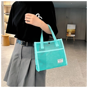 Close-up of light blue mesh tote bag with white logo label and black snap button