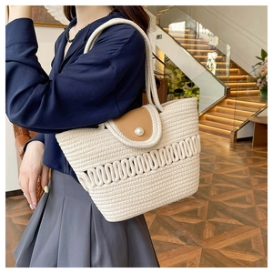 Detail of hand-woven straw tote bag with brown leather flap and pearl buckle