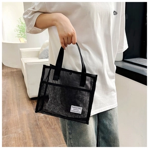 Detail of black mesh tote bag showing durable nylon material and dual handles with label