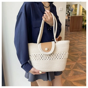 Detail of hand-woven off-white tote bag with wave texture and large pearl buckle closure