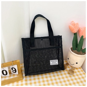 Detail view of breathable black mesh tote bag featuring woven label and snap button closure