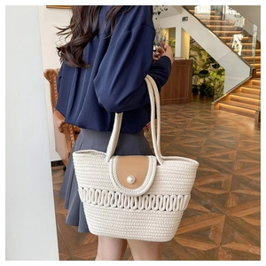 Detail of woven straw tote bag with pearl closure and brown leather flap on a model