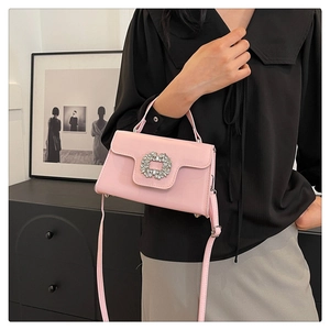 Détail du sac en cuir verni rose clair avec une boucle ronde étincelante en strass