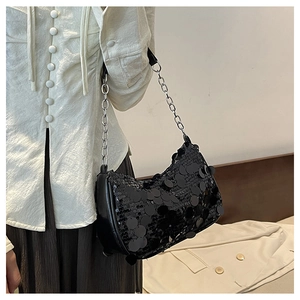 Détail d'un sac demi-lune à paillettes noires avec une grosse chaîne argentée sur modèle