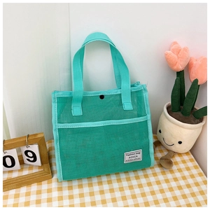 Close-up of mint green breathable mesh tote bag with textile handles on a plaid table