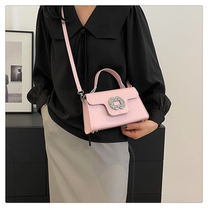 Détail d'un sac bandoulière en cuir rose avec une boucle sertie de strass brillants