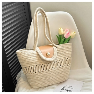 Macro detail of hand-woven straw tote with pearl buckle and leather flap on a white chair