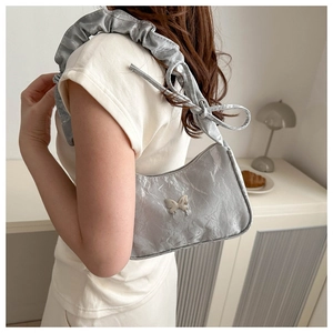 Silver shoulder bag with pleated texture, butterfly metal ornament, and knotted strap